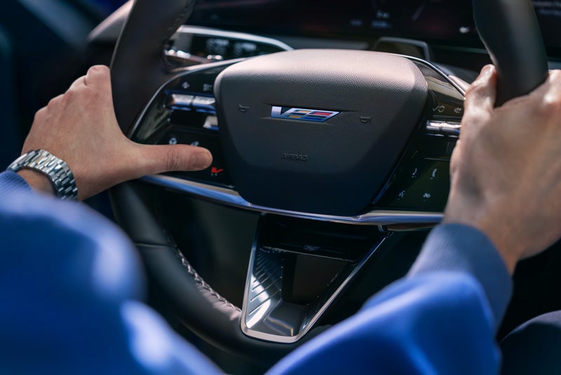 Close-up of a Man About to Press the V-Button on the 2026 OPTIQ-V Steering Wheel | James E. Black Cadillac in Ebensburg PA
