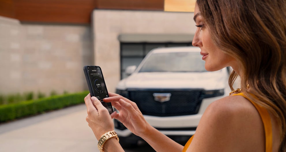 lady checking her mobile with a Cadillac vehicle background | James E. Black Cadillac in Ebensburg PA